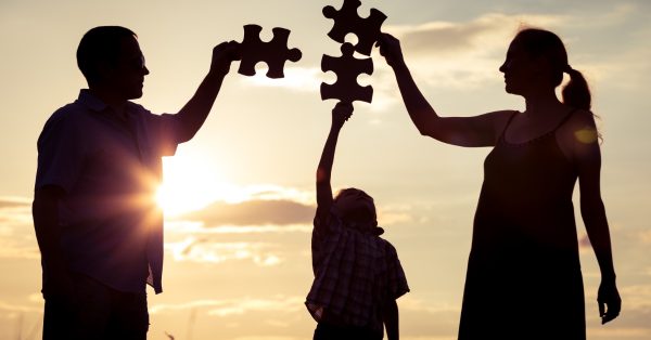 Happy family standing in the park at the sunset time. People having fun outdoors. Concept of friendly family.